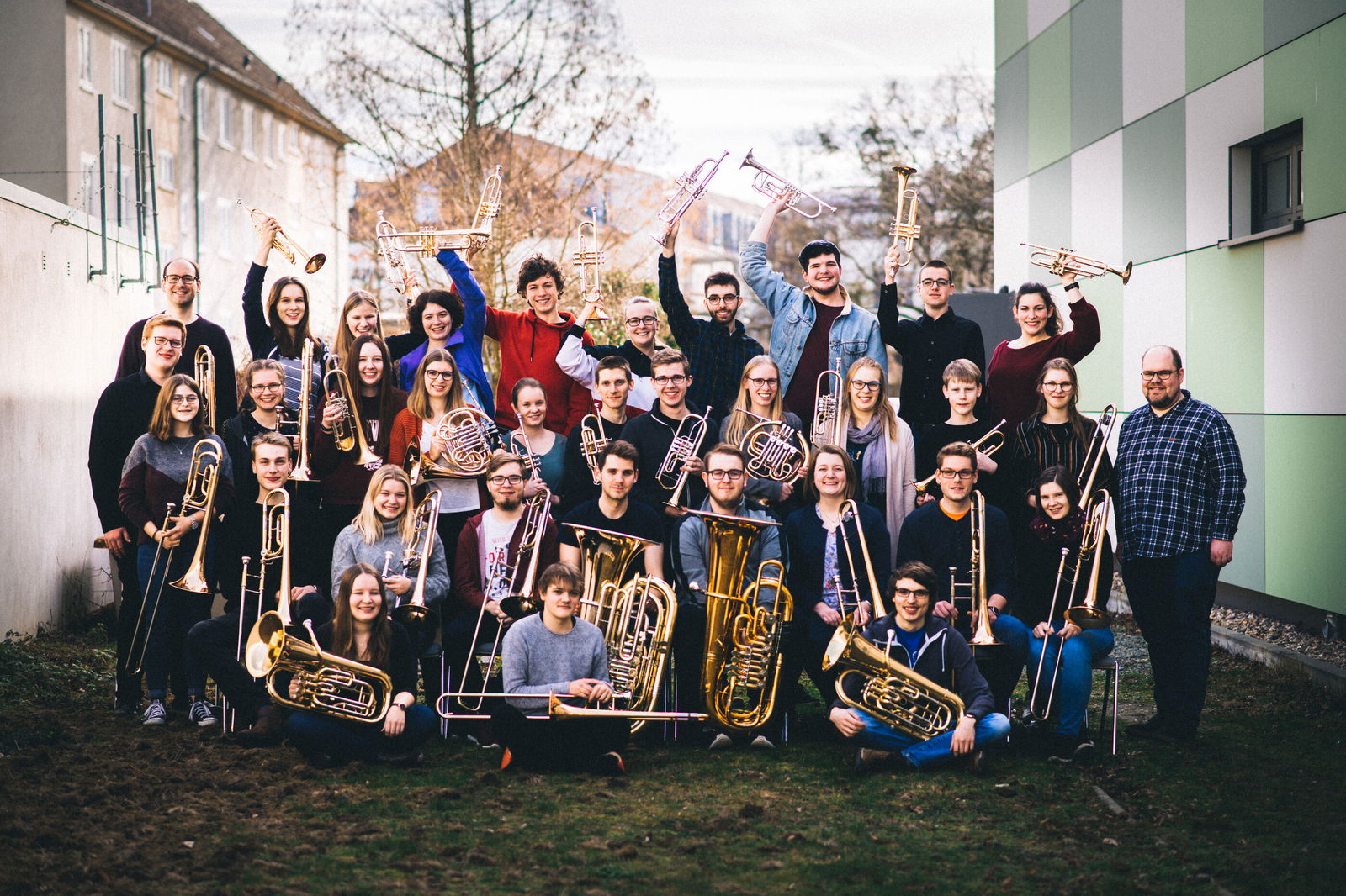 Etwa dreißig junge Menschen stehen und knien zusammen für ein Gruppenfoto, sie halten Blasinstrumente in Händen.