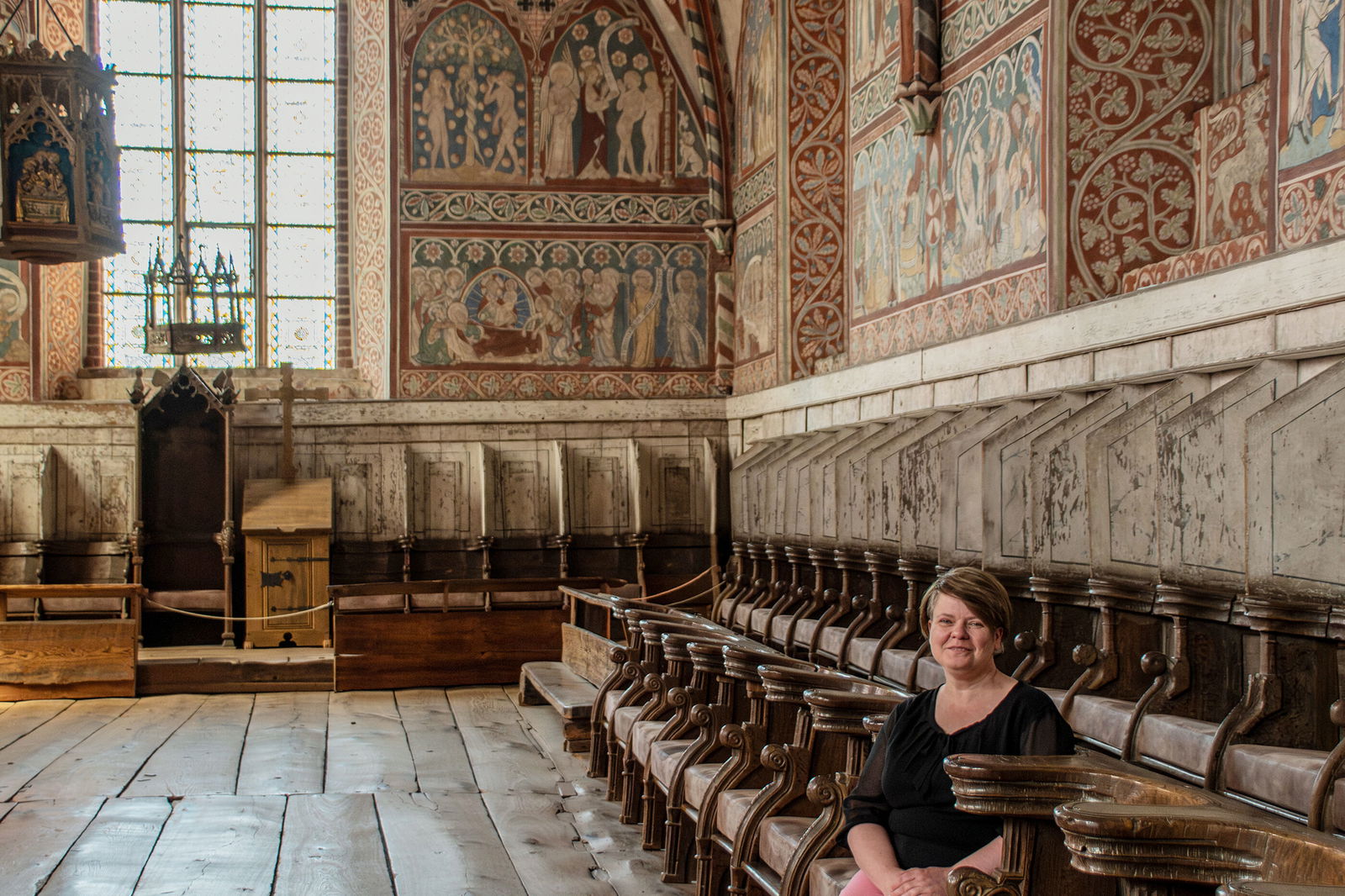 Eine Frau sitzt im Chorgestühl eines Klosters. 