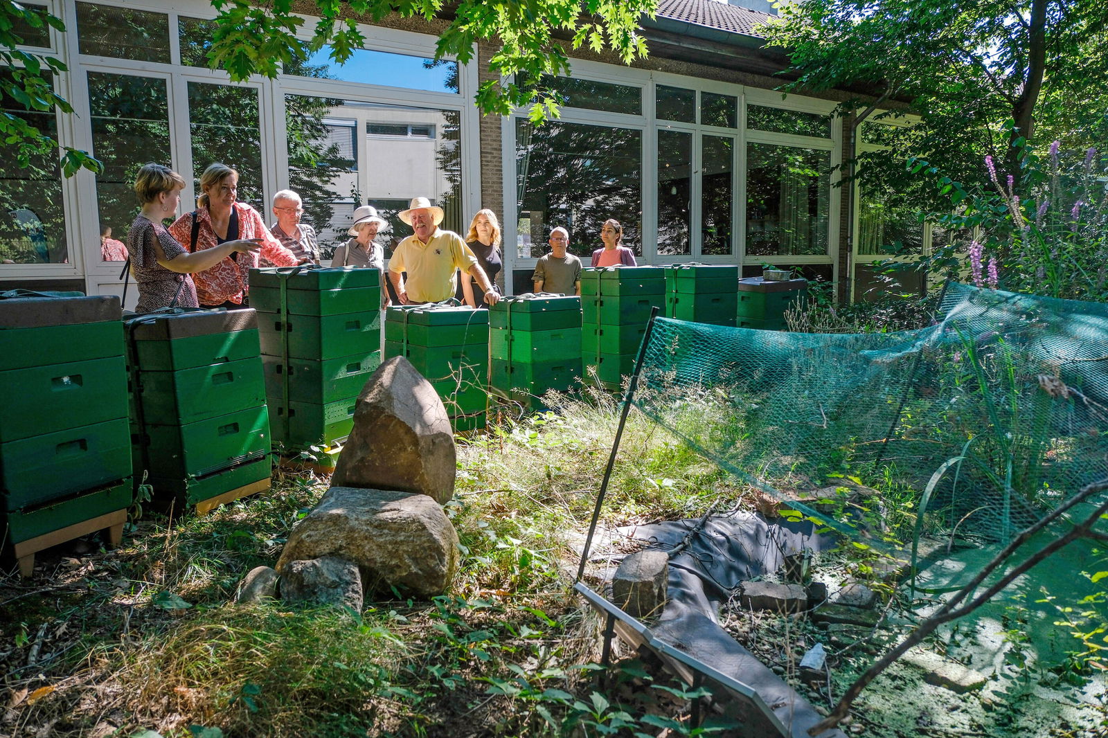 Menschen stehen im Grünen vor einem Gehege.