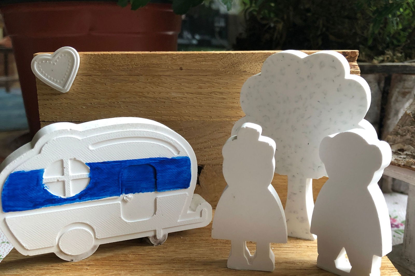 ein Miniatur-Wohnwagen aus Holz mit Figuren daneben