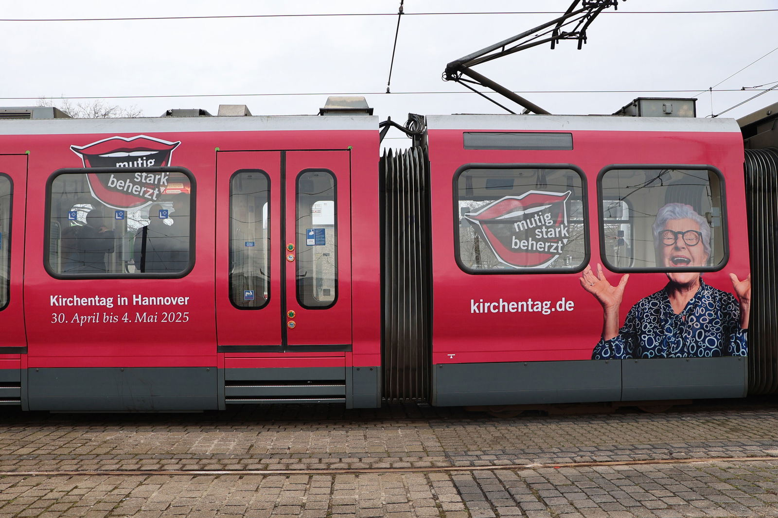 Eine rote Straßenbahn mit Kirchentagswerbung.