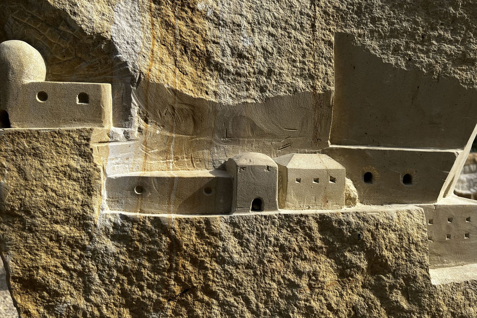 In einen Sandstein gehauen sind mehrere Gebäude zu erkennen.