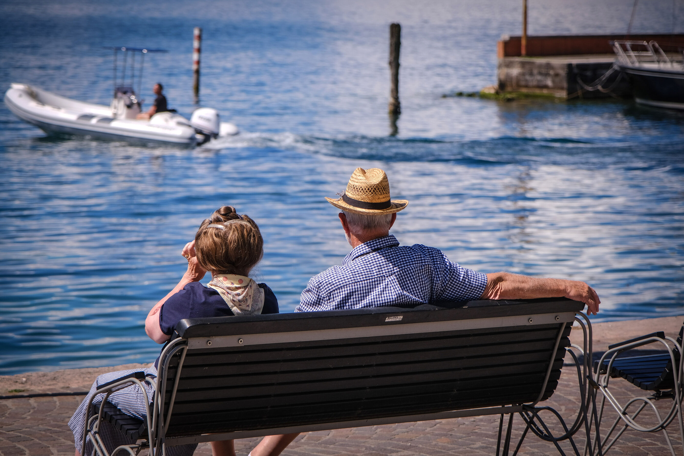 Zwei Menschen sitzen auf einer Bank am Wasser.