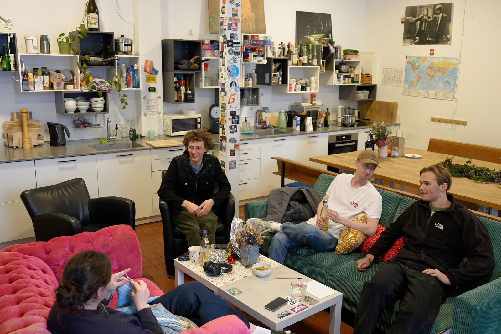 Vier Personen sitzen in einer Küche an einem kleinen Tisch.