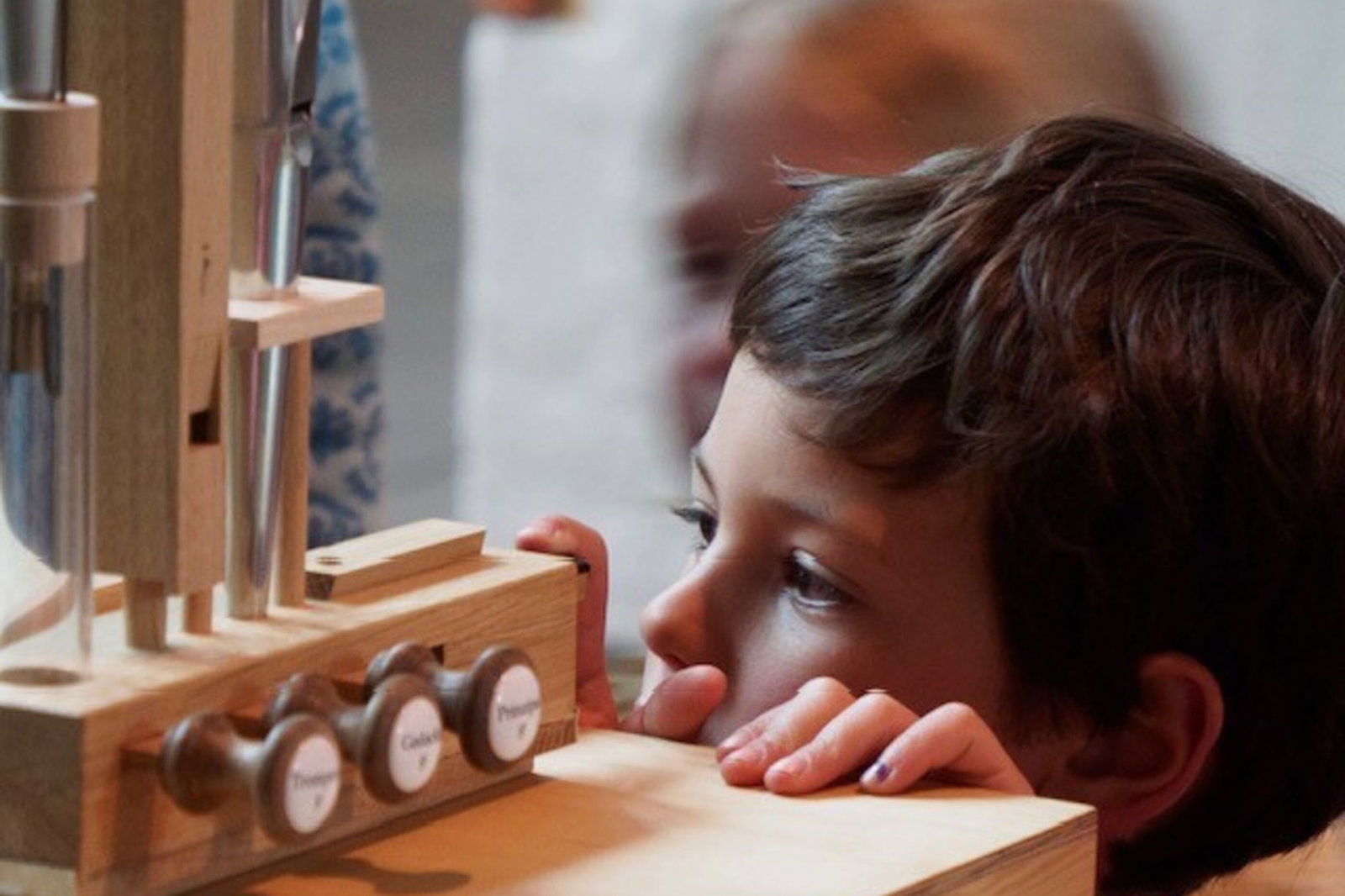 Ein Kind betrachtet eine Holzkonstruktion aus der Nähe.
