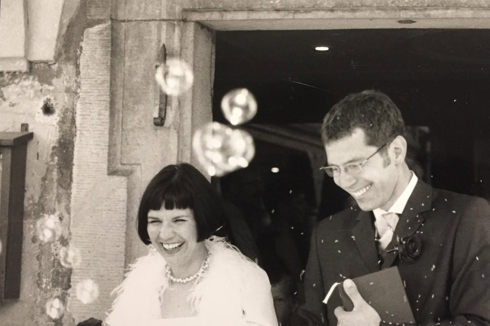 Eine Braut und ein Bräutigma verlassen strahlend eine Kirche - schwarz-weiß-Bild.