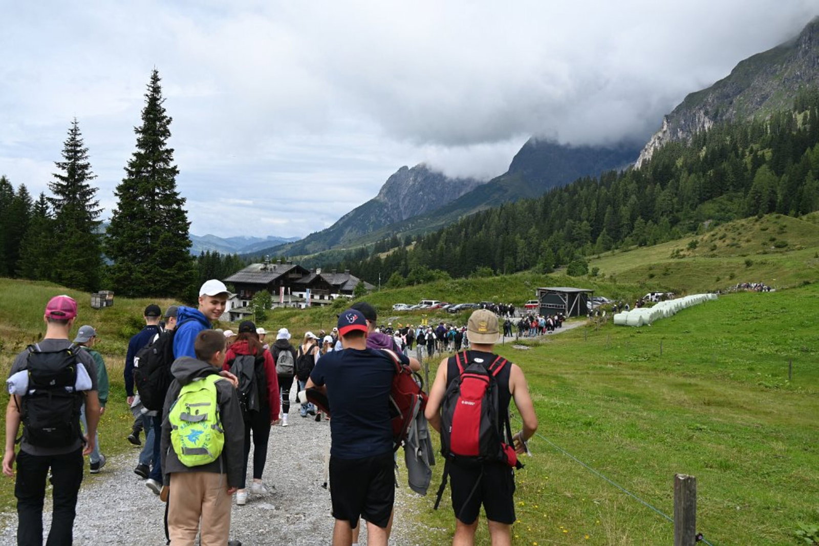 Junge Menschen sind von hinten zu sehen, wie sich zwischen Bergen wandern.