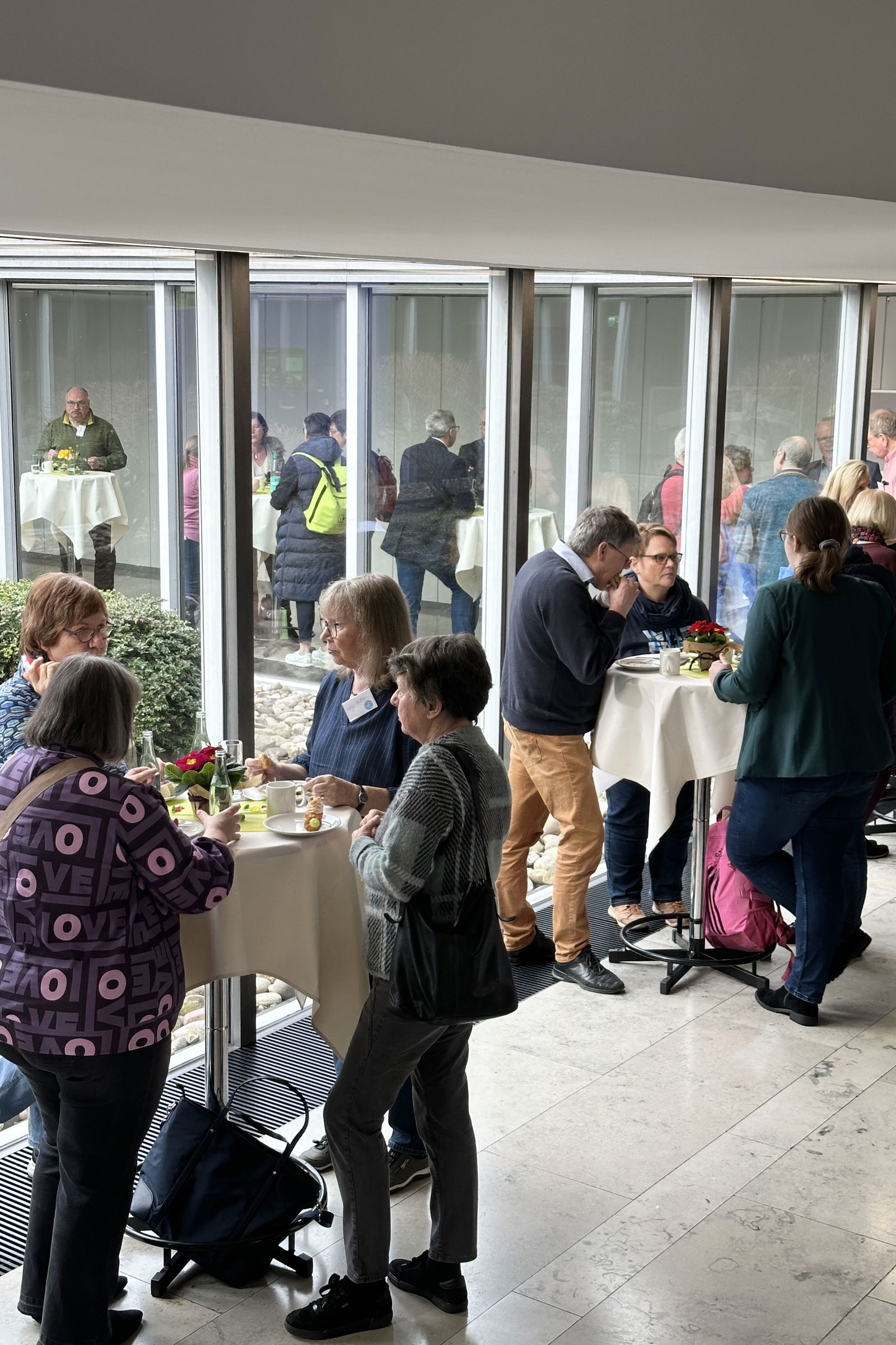 Menschen stehen an Stehtischen zusammen.