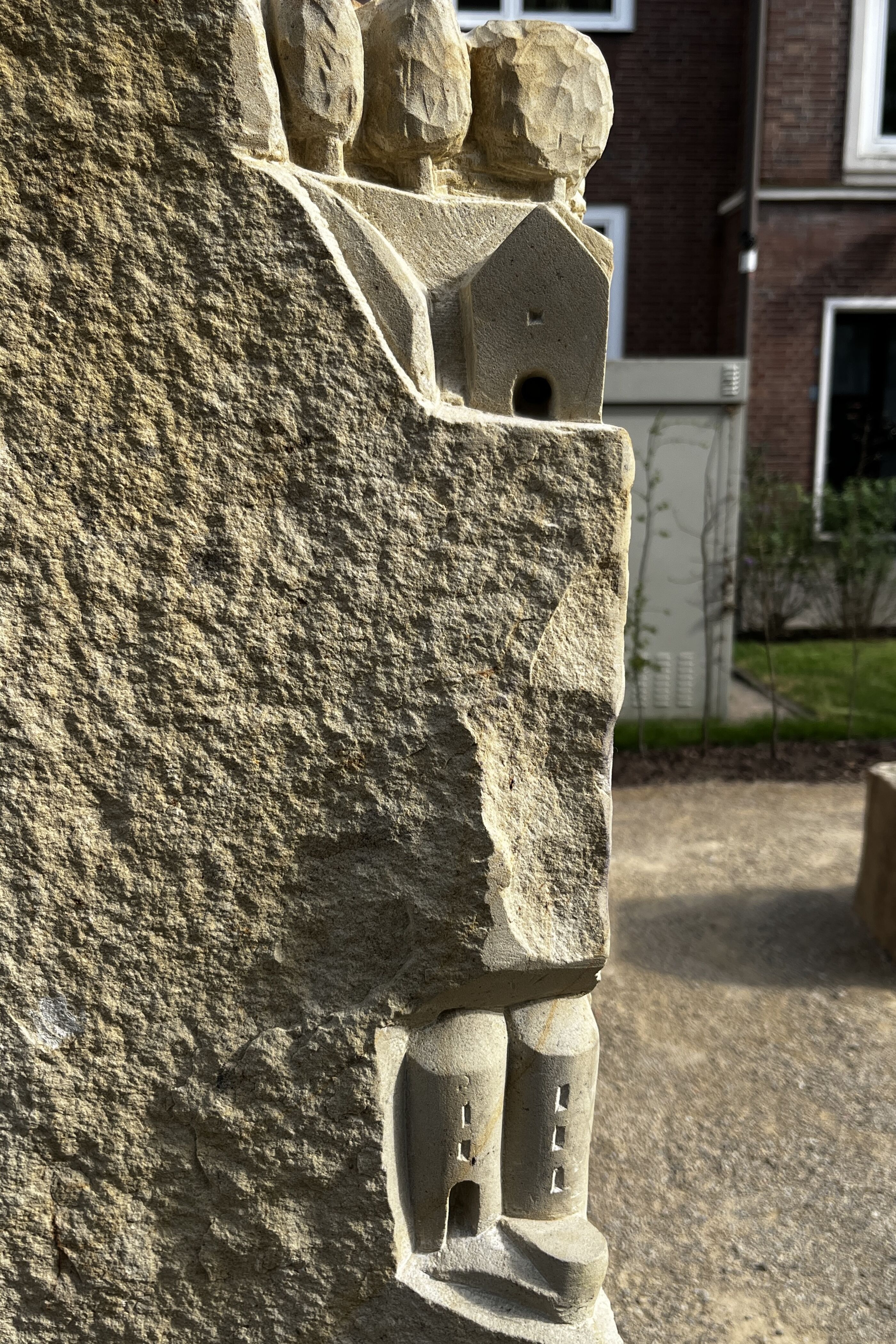 In eine Sandsteinstele sind mehrere Gebäudeumrisse gehauen.