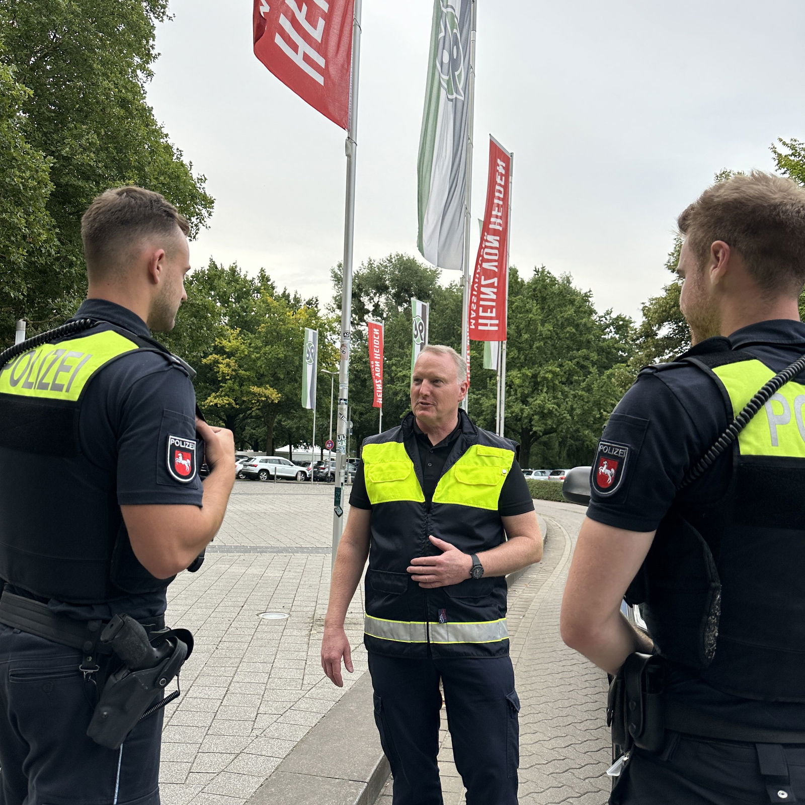 Drei männlich gelesene Personen in Polizeiuniform.