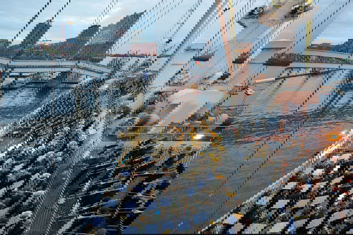 Ein riesige Blasensemble spielt auf einem Schiff, im Hintergrund ist die Hamburger Elbphilharmonie zu sehen.