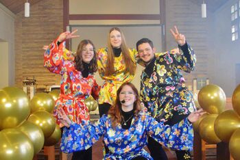 Eine Gruppe von Jugendlichen hat sich mit Abba-Kostümen verkleidet und hat sich in der Kirche aufgestellt zu einem Gruppenfoto.