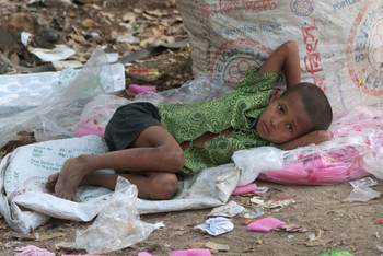 Junge schläft neben Müllsack. Bild: epd