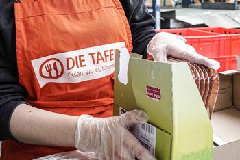 Ein Mitarbeitender der Osnabrücker Tafel verpackt Lebensmittel.