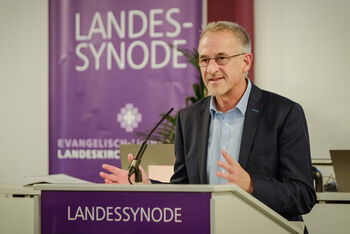 Eine männlich gelesene Person am Redepult. 