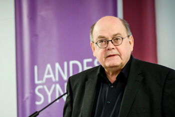 Eine männlich lesbare Person an einem Rednerpult