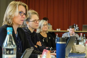 Mehrere weiblich lesbare Personen hören jemandem zu