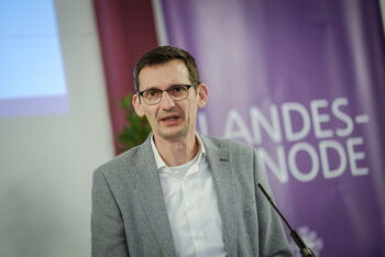 Eine männlich zu lesende Person spricht in ein Standmikrofon.