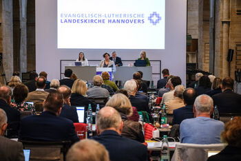 Mehrere Personen aus dem Plenum hören der vortragenden Person zu.