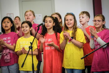 Mehrere Kinder, die singen und die Hände falten