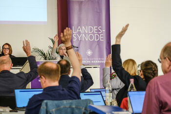 Mehrere Personen heben die Hand zur Abstimmung