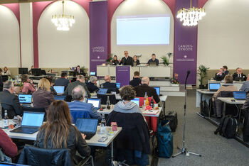 Viele Personen an Tischen in einem Sitzungssaal