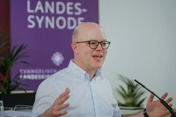 Eine männlich lesbare Person an einem Rednerpult