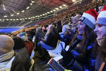 Menschen mit Weihnachtsmuetzen in einem Stadion