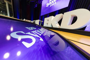 Ein Bildschirm zeigt: Synode. Im Hintergrund drei übergroße Buchstaben auf einer Bühne: EKD