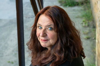 Eine als Frau lesbare Person mit schulterlangen rotbraunen Haaren.