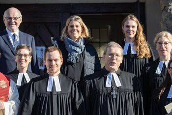 Menschen in Festkleidung vor einer Kirche.