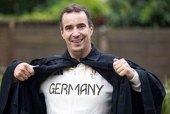 Eine als Mann lesbare Person präsentiert ein Germany-Trikot.