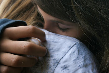 Eine als Frau lesbare Person tröstet ein Kind