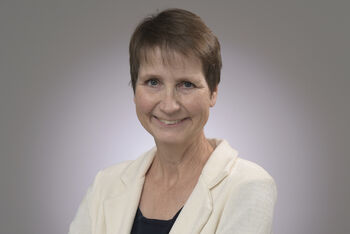 Eine als Frau lesbare Person im weißen Blazer.