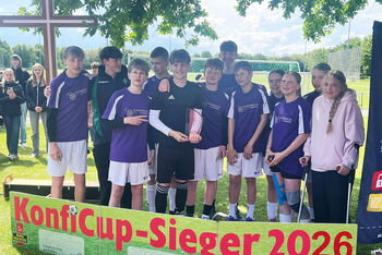 Eine Fußballmannschaft steht hinter einem Banner mit der Aufschrift KonfiCup-Sieger 2026.