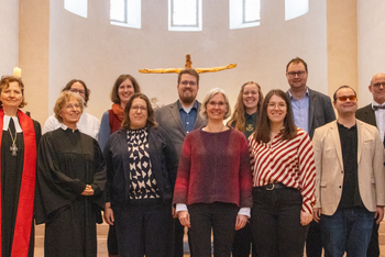 Etwa ein dutzend Menschen stehen zusammen in einer Kirche.