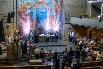 Mehrere Menschen stehen in einer Kirche und feiern Abendmahl.