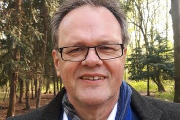 Eine als Mann lesbare Person mit Brille, hoher Stirn und kurzen Haaren.