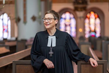 Eine als Frau lesbare Person im Talar in einer Kirche.