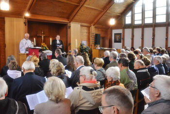 Zwei als Männer lesbare Geistliche in einer vollbesetzten Kirche