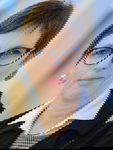 Eine weiblich gelesene Person mit kurzen dunklen Haaren und einer Brille mit dunkler Fassung. 