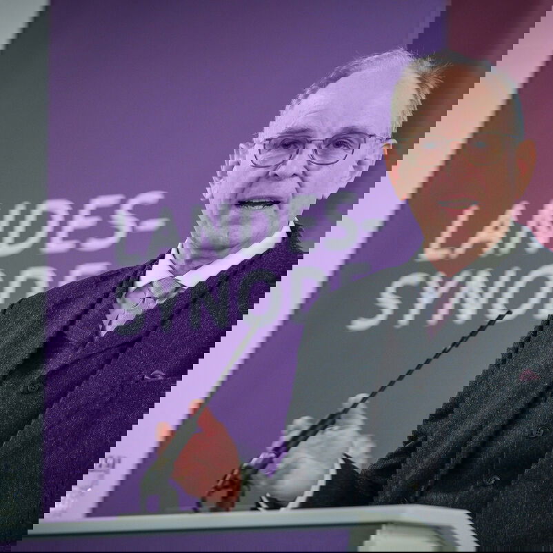 Eine männlich lesbare Person an einem Rednerpult