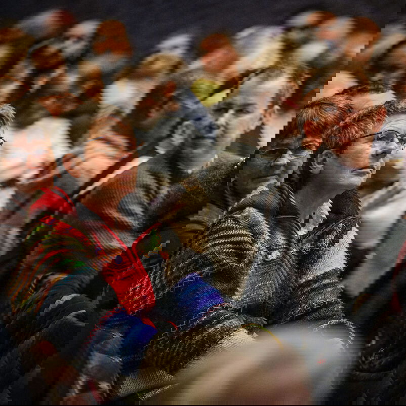 Blick in ein bunt gemischtes Publikum, Frauen und Männer, ältere und jüngere, verschiedener Herkünfte.