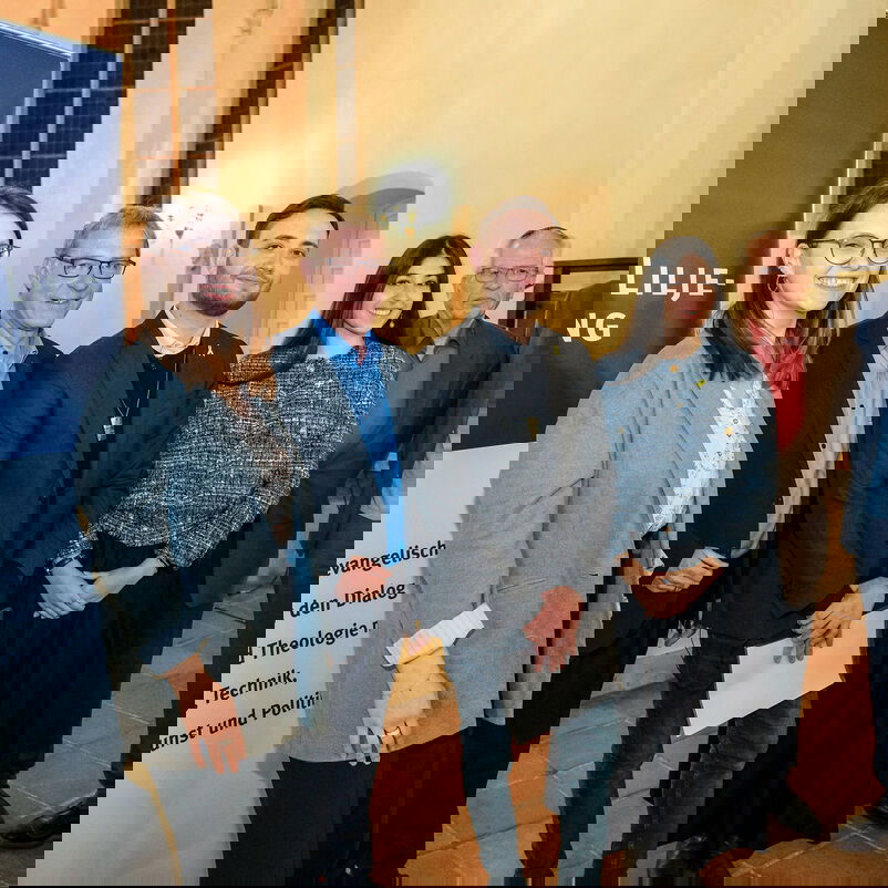 Sechs Personen stehen nebeneinander, links ein Banner, auf dem steht "Hanns-Lilje-Stiftung"