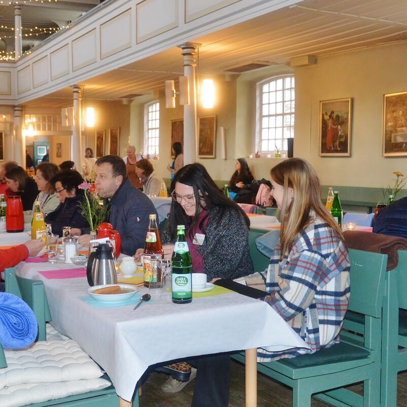 Menschen sitzen an Tischen und essen.