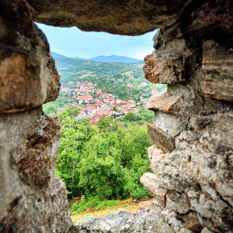 Blick durch eine steinerne Fensteröffnung auf eine Landschaft.