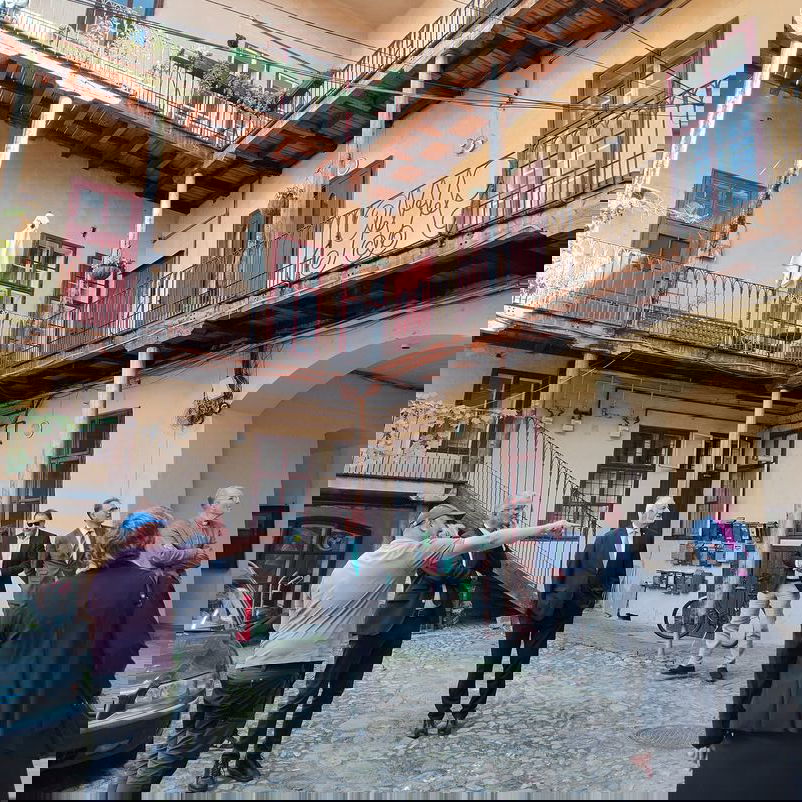 Eine Gruppe von männlich und weiblich zu lesenden Person steht im Innenhof eines Gebäudes und diskutiert.