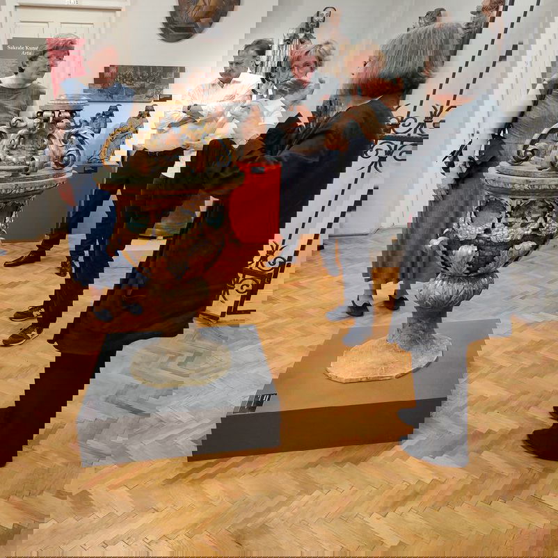 In einem Raum ist ein künstlierisch gestalteter Taufstein ausgestellt.