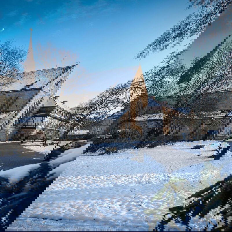 Eine Kirche und eine Klosteranlage mit schneebedeckten Wegen.