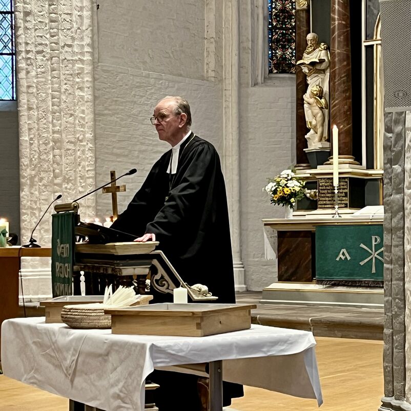 Ein Mann im Talar an einem Altar.